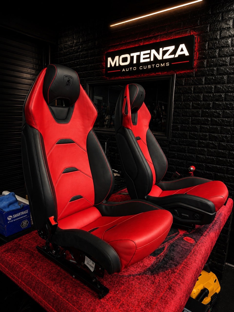 Red and black Lamborghini leather seats on a workshop bench, with shaped side bolsters and contrasting upholstery panels